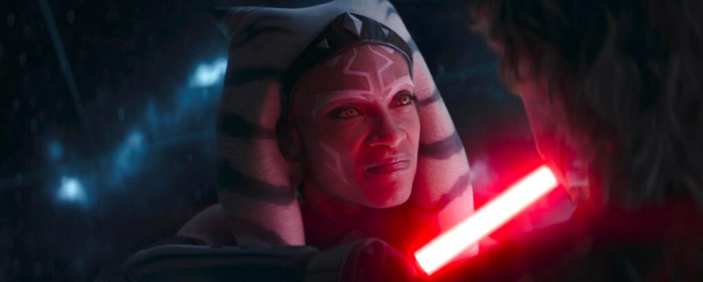 Ahsoka Tano faces down Anakin Skywalker, holding his red lightsaber to his throat, her eyes turning Sith-yellow.