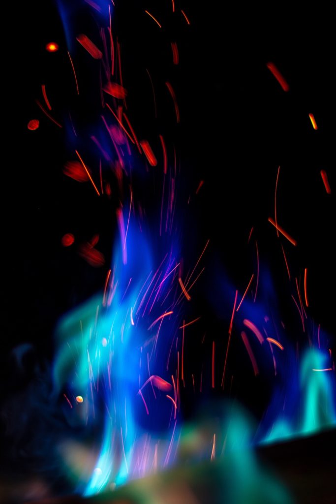 Blue flame and red sparks dance against a black background.