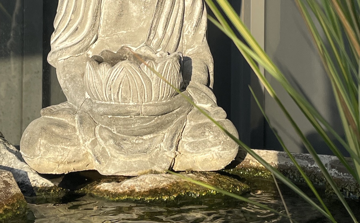 The lower portion of a statue of the Buddha, resting by flowing water.