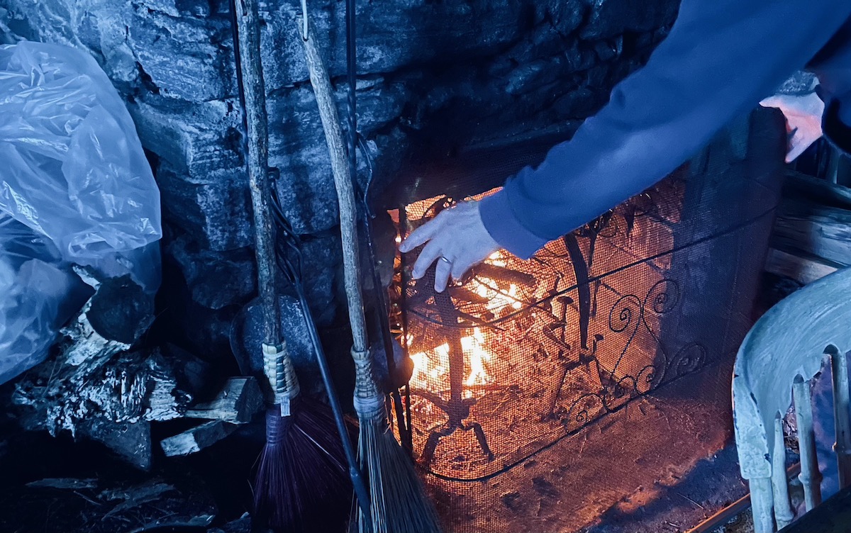 A stone fireplace warming up, in a cold-blue room.