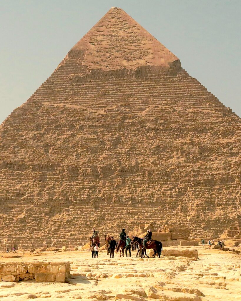 A group of people site astride horses before the Great Pyramid of Giza.