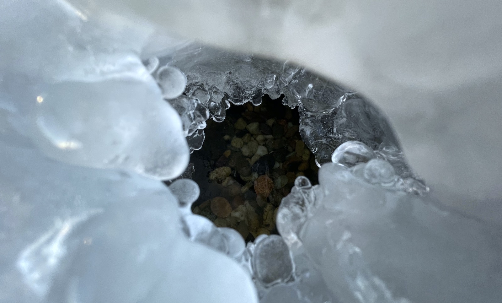 A tunnel through ice reveals water and stone beneath.